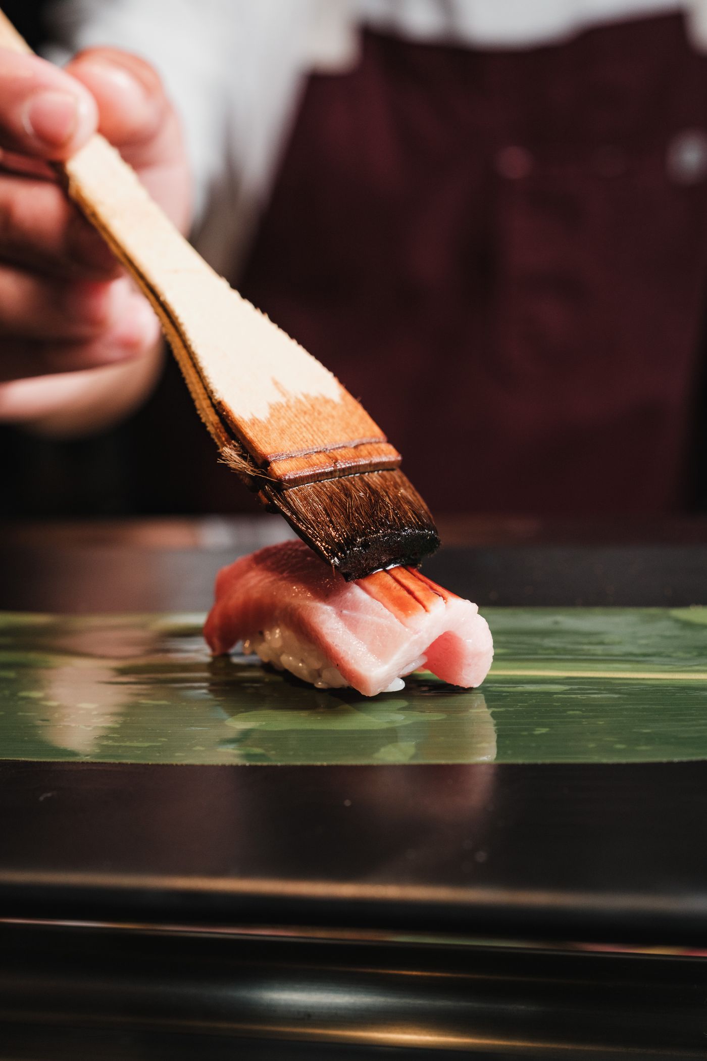 Kokken pensler soyaglasur over en nigiri ved disken